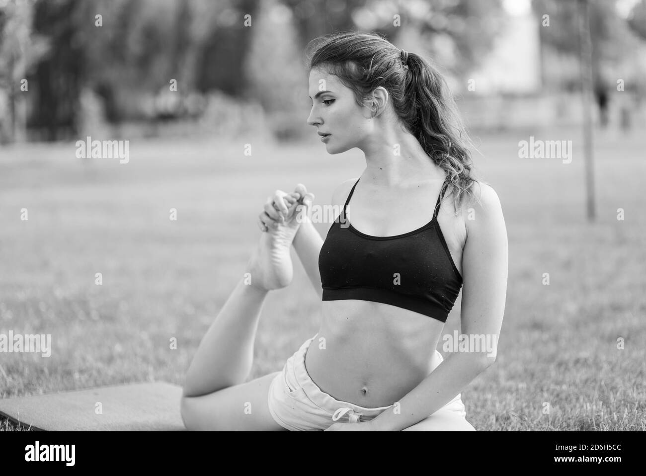 Girl doing yoga in the park during the day. Black and white photo. BW Stock Photo