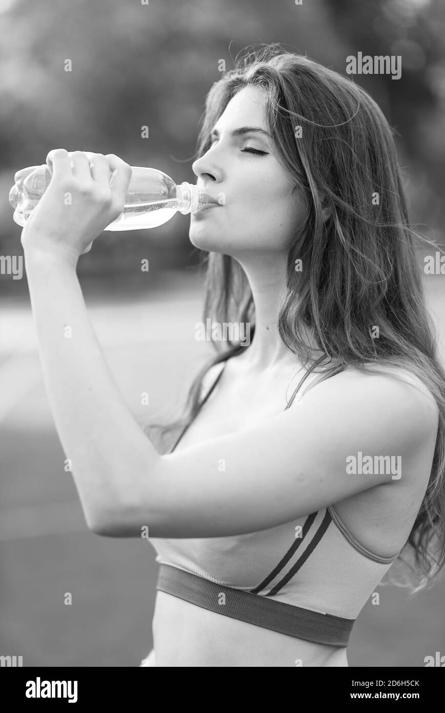 Girl athlete drinks water during a break in sports. Black and white photo. BW Stock Photo