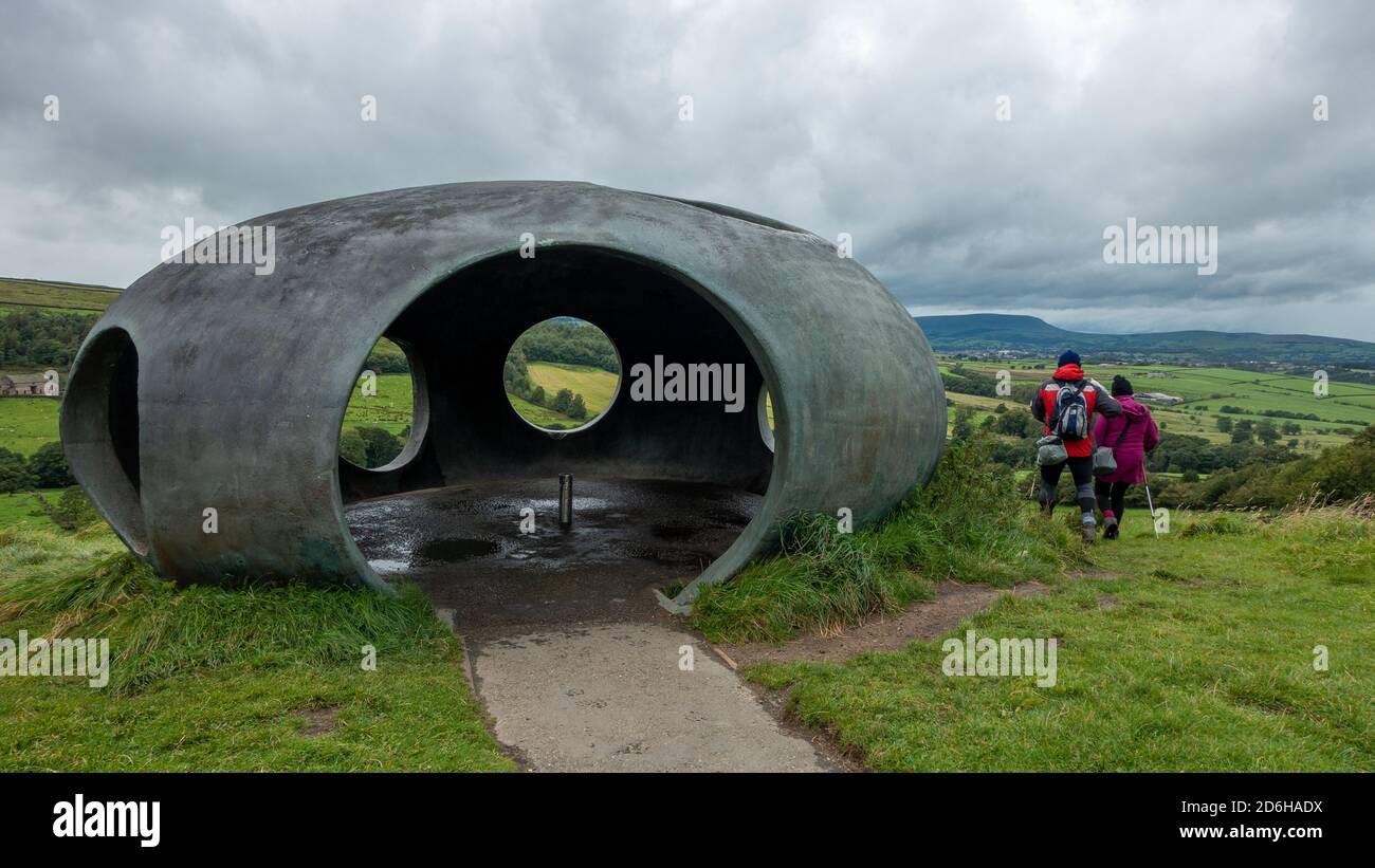 Three walkers visit The Atom Panopticon: a concrete dome in stunning countryside on a rainy summer's day during Storm Francis, Wycoller Stock Photo