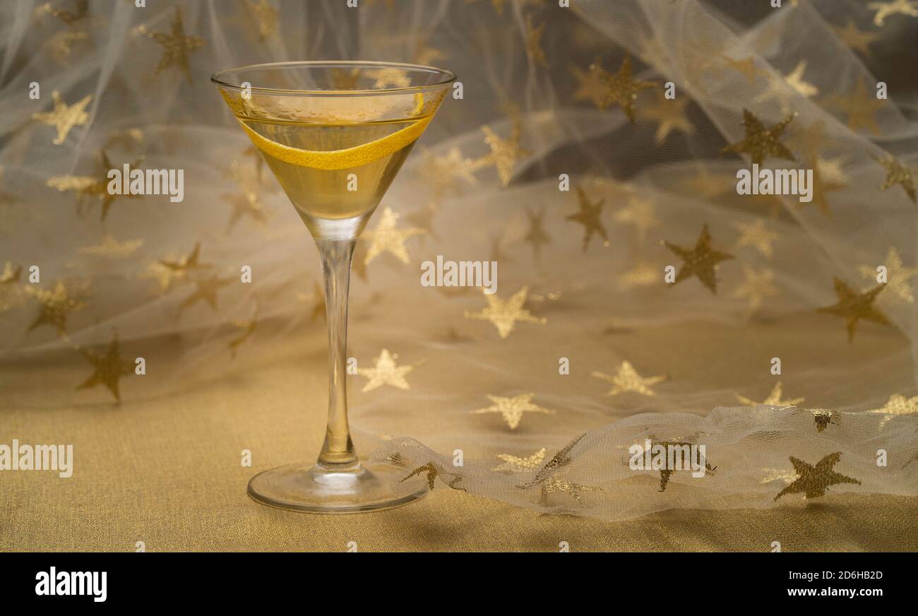 Vodka Martini cocktail with lemon twist on golden fabric with starry background Stock Photo