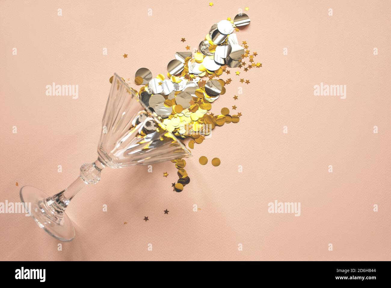 Wine glass with gold sparkles or confetti on a pink background