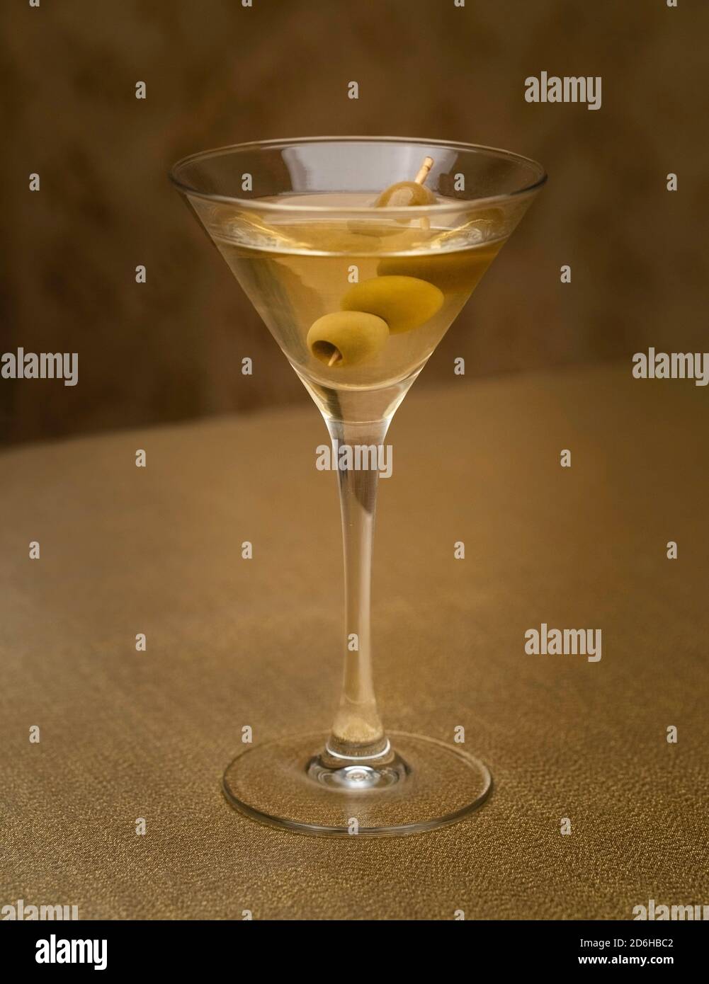 vodka martini cocktail with olives indoors on golden fabric Stock Photo