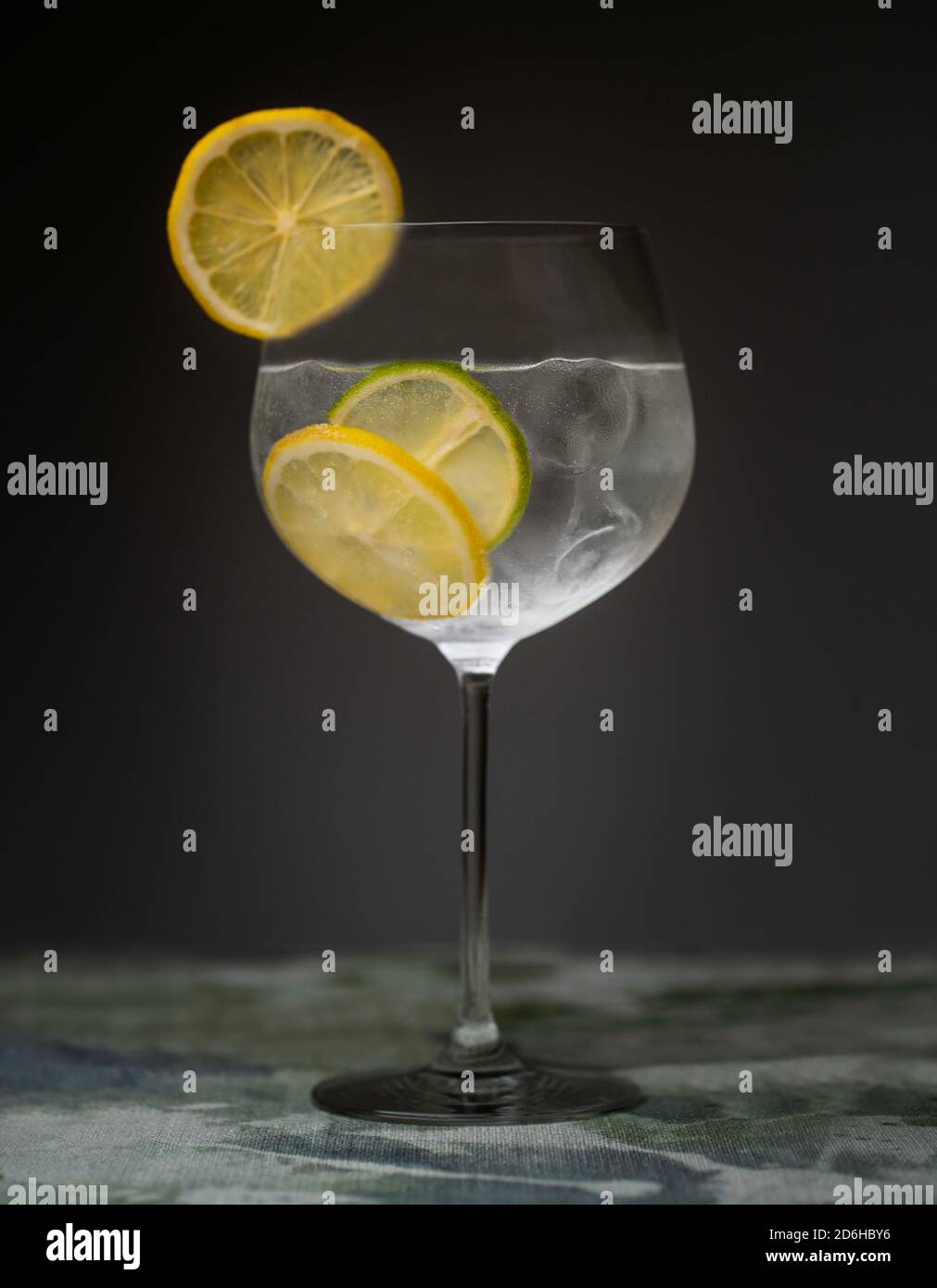 Gin and tonic cocktail drink indoors with ice, lemon and lime Stock Photo