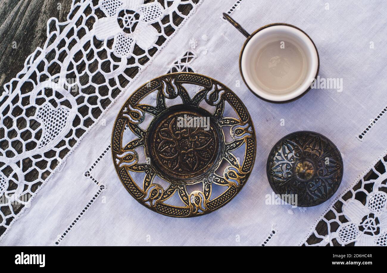 Turkish coffee cups with a glass of water on a wooden table with a white cloth photographed from above Stock Photo