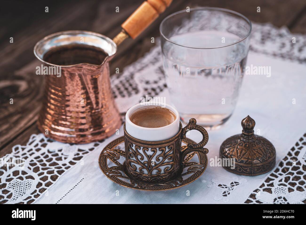 Turkish coffee cups with a glass of water on a wooden table with a white cloth photographed from above Stock Photo