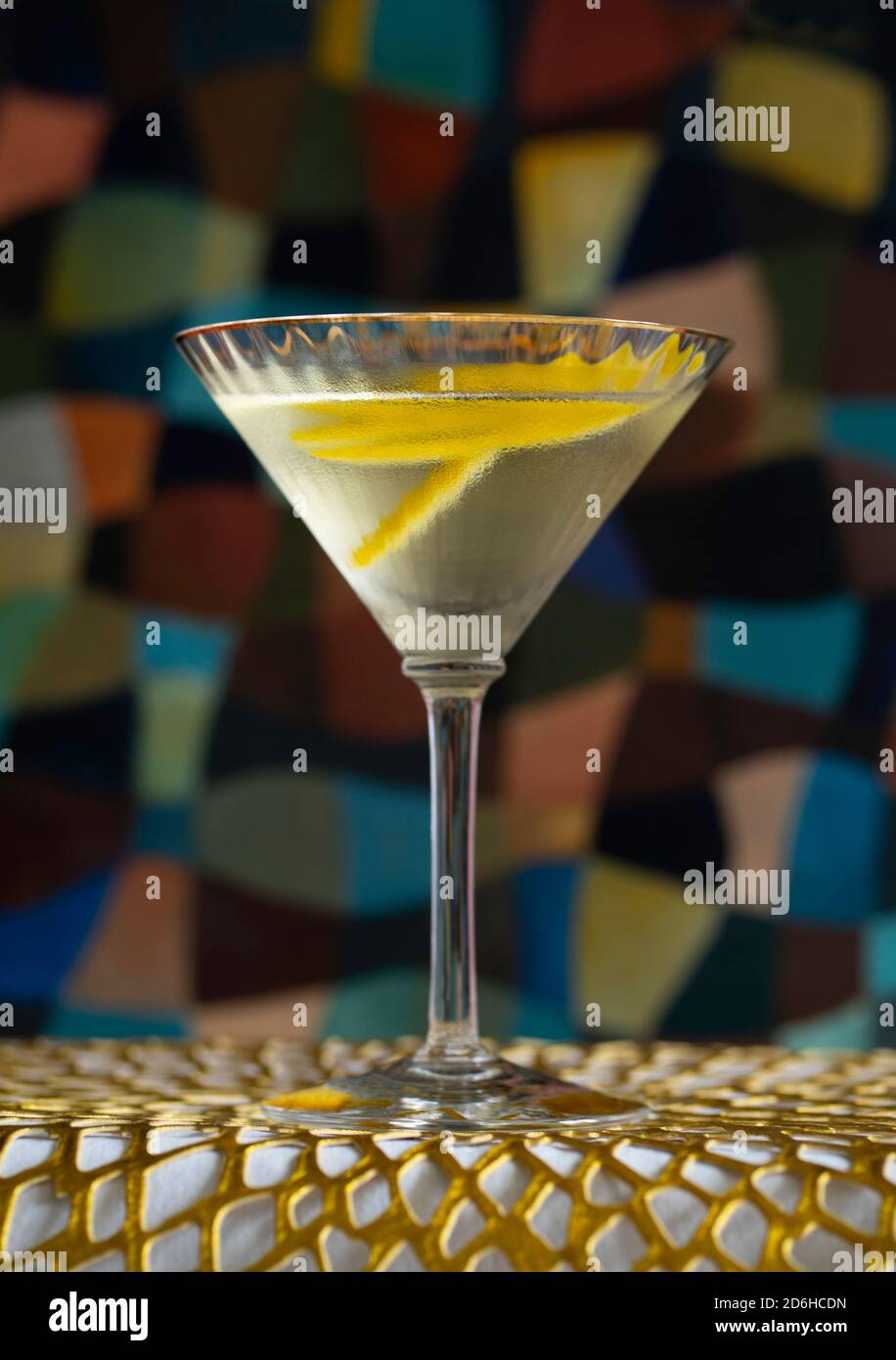 Vesper martini cocktail drink on golden mat in front of a painting