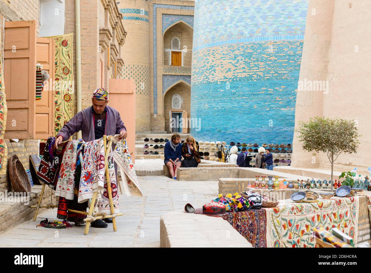 Souvenir shopkeeper arranging suzani (embroidery) blankets in the old centre of Khiva, Uzbekistan Stock Photo