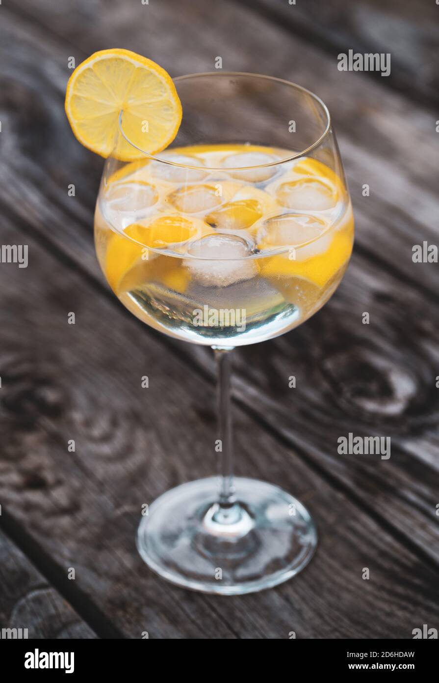 Glass of Gin and Tonic with pieces of lemon on a wooden table Stock Photo