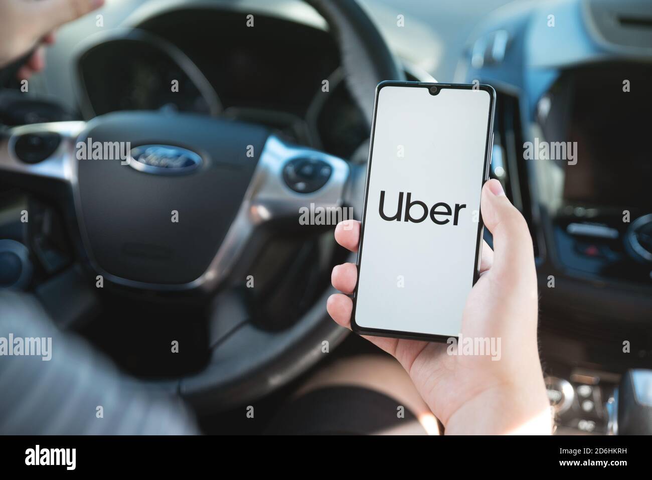 Wroclaw, Poland - AUG 25, 2020: Uber driver holding smartphone in car. Uber is sharing-economy service for ubran transport. Stock Photo