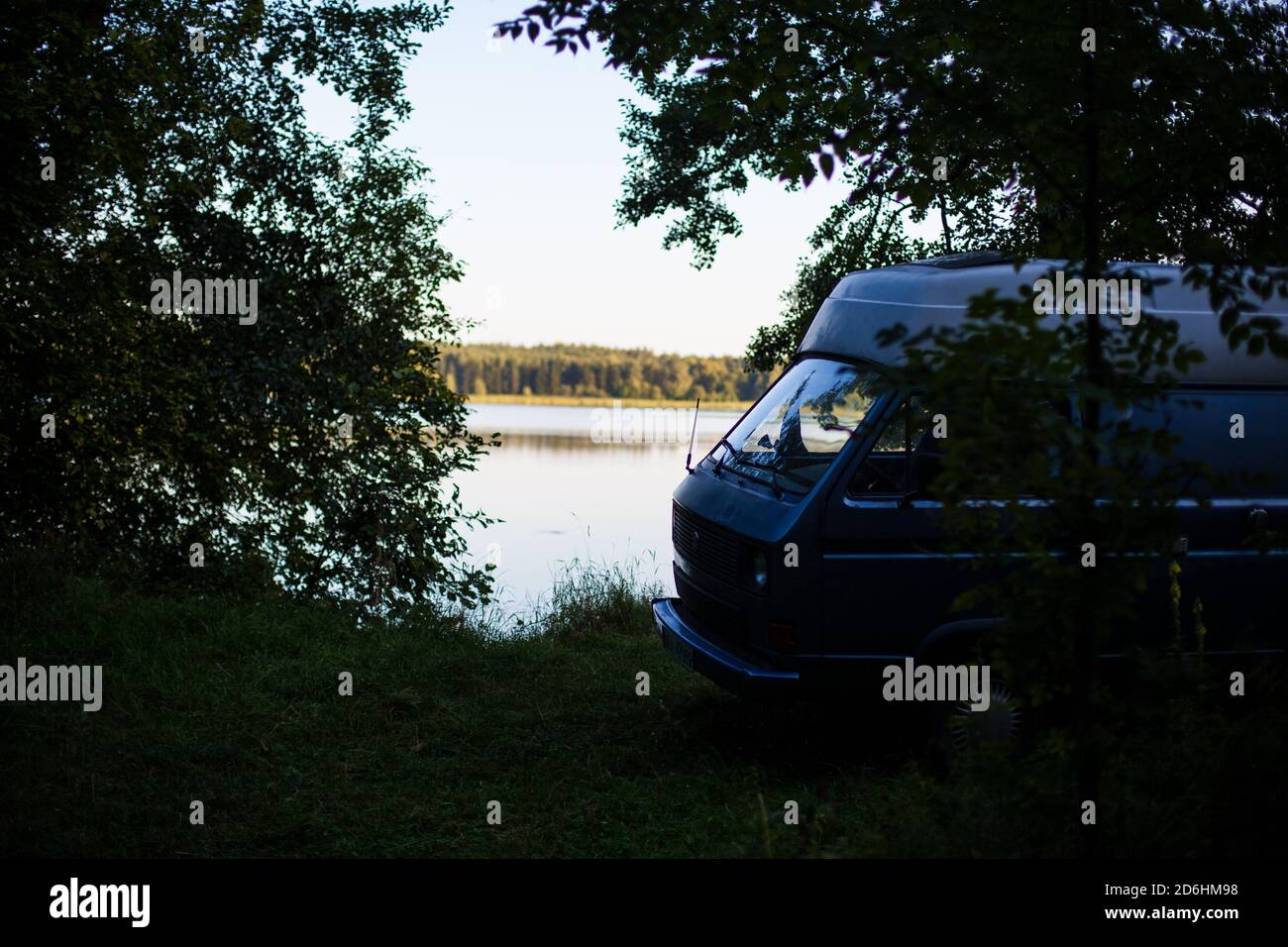 Old campervan hidden in the forest by coast Stock Photo