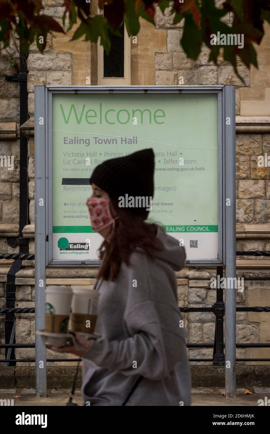 London, UK.  17 October 2020. A woman wearing a facemask passes the Town Hall in Ealing, west London.  The Office for National Statistics (ONS) has reported that the confirmed coronavirus cases in the capital exceed 67,000, with Ealing having the highest Covid-19 rate amongst London Boroughs at 144 cases per 100.  Following the UK Government’s announcement, the capital has today moved from Tier 1 to Tier 2, meaning a ban on indoor social mixing between households in the capital.  Credit: Stephen Chung / Alamy Live News Stock Photo