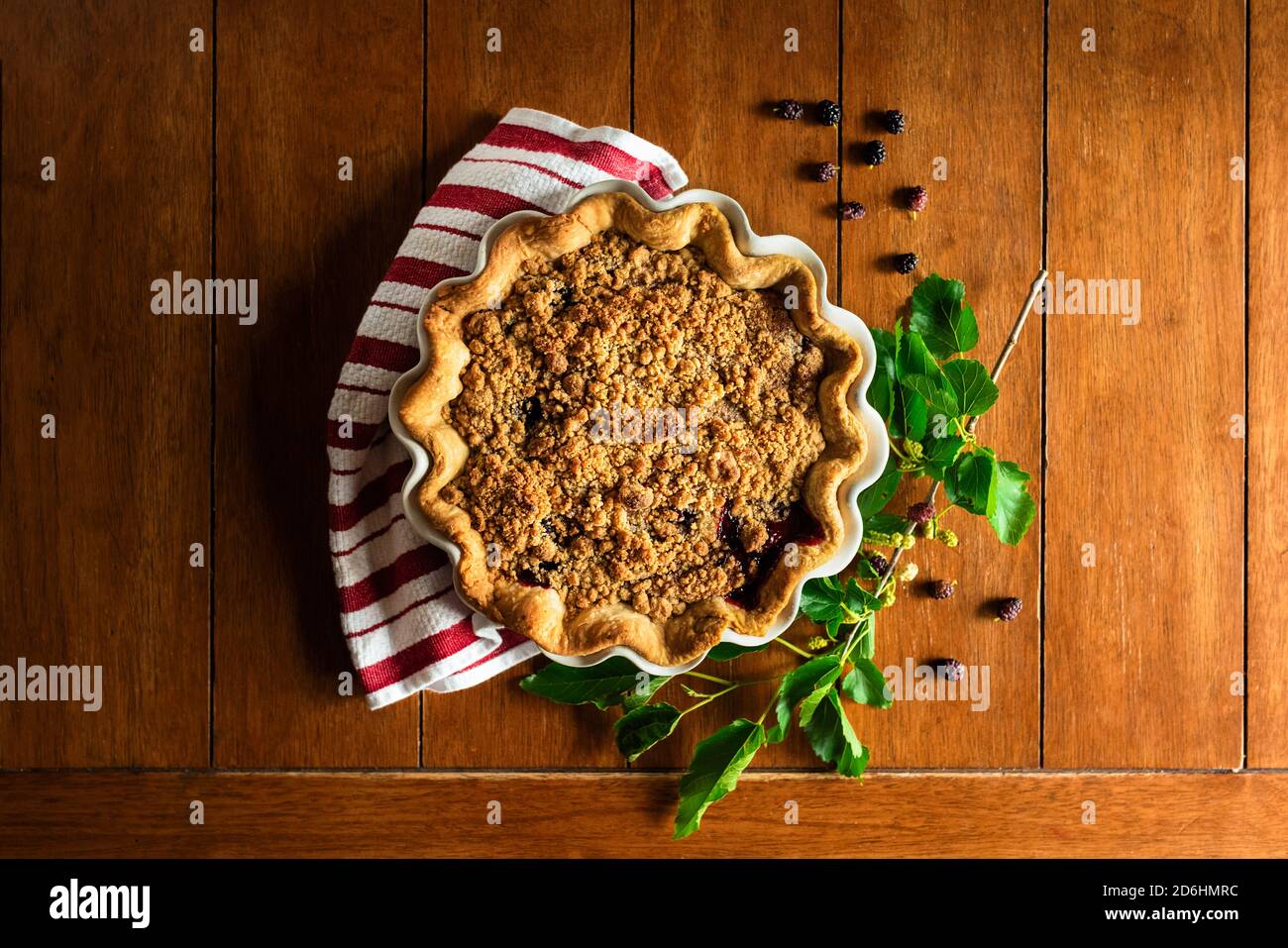 blackberry pie sitting on a kitchen table with a striped dish towel Stock Photo