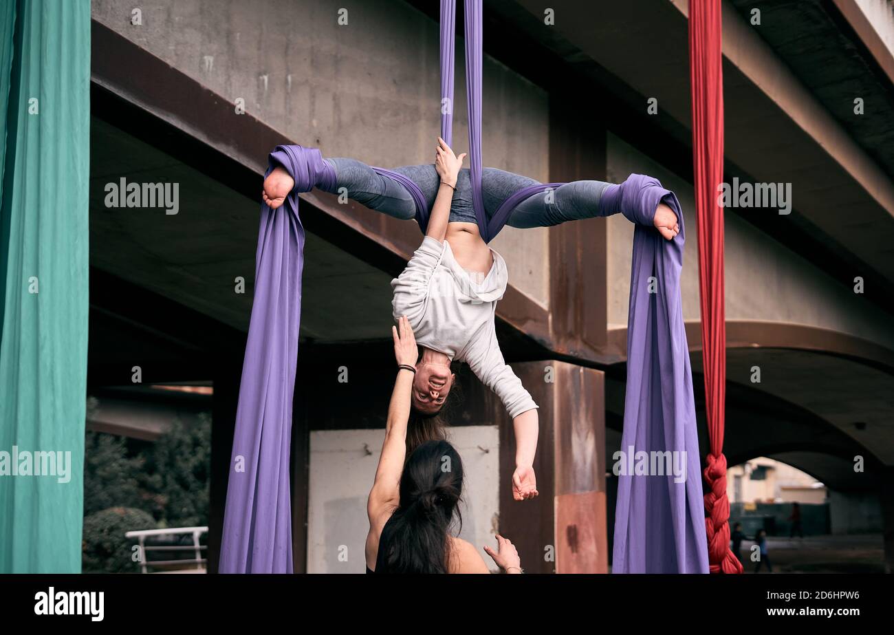 Caucasian woman teaching her friends how to do some aerial silks