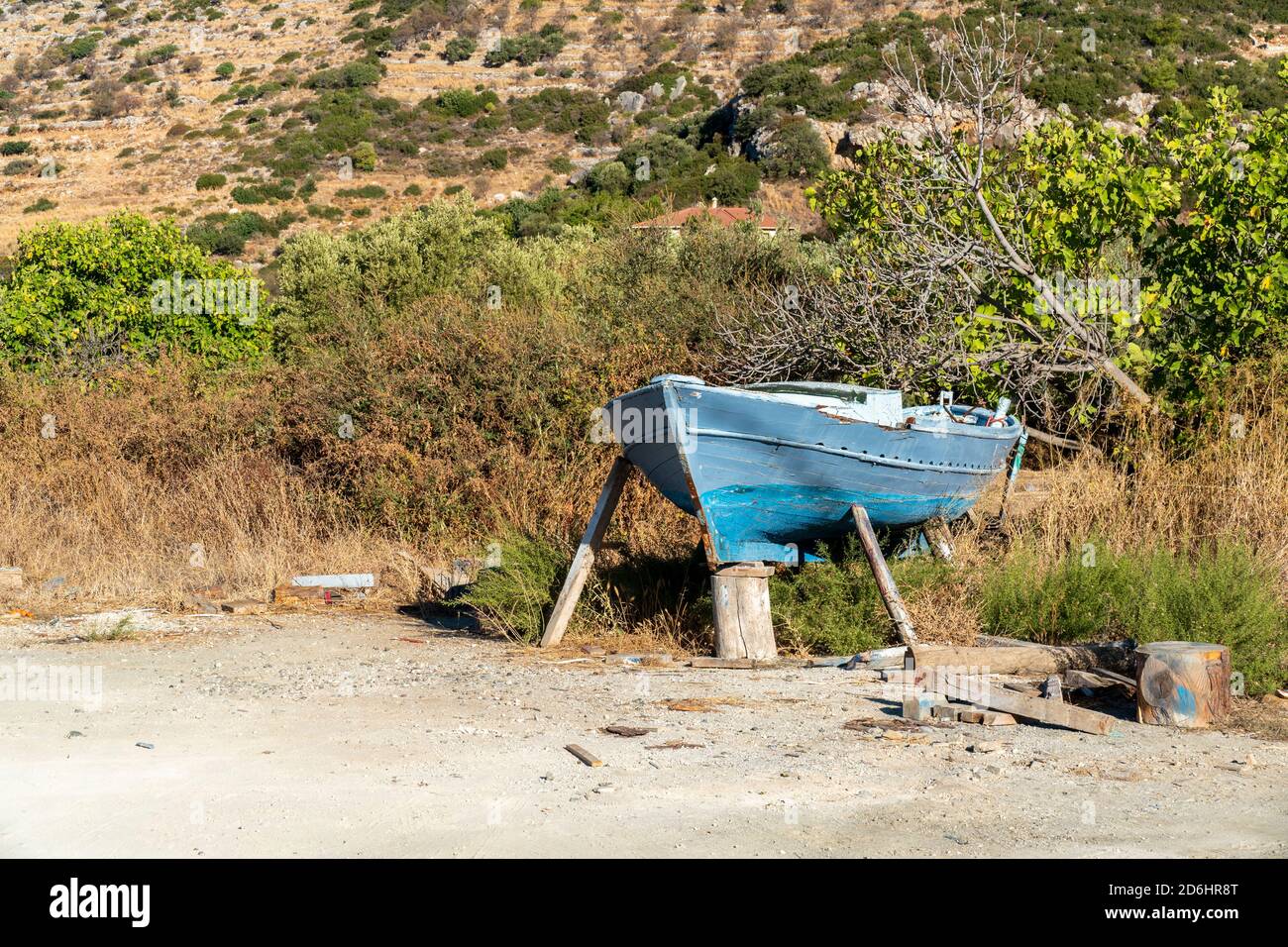 An abandoned little fisher boat discarded at land. The wood of the blue colored ship wreck looks very weathered. In the background green grass. Stock Photo