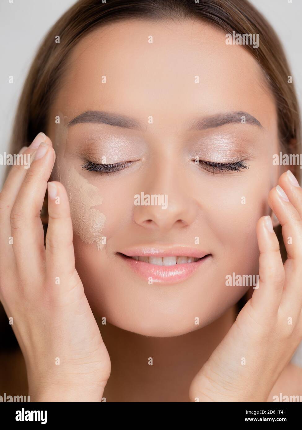 Foundation on the cheek, portrait of a young beautiful woman with beautiful clear skin. Well-groomed skin and makeup. Stock Photo