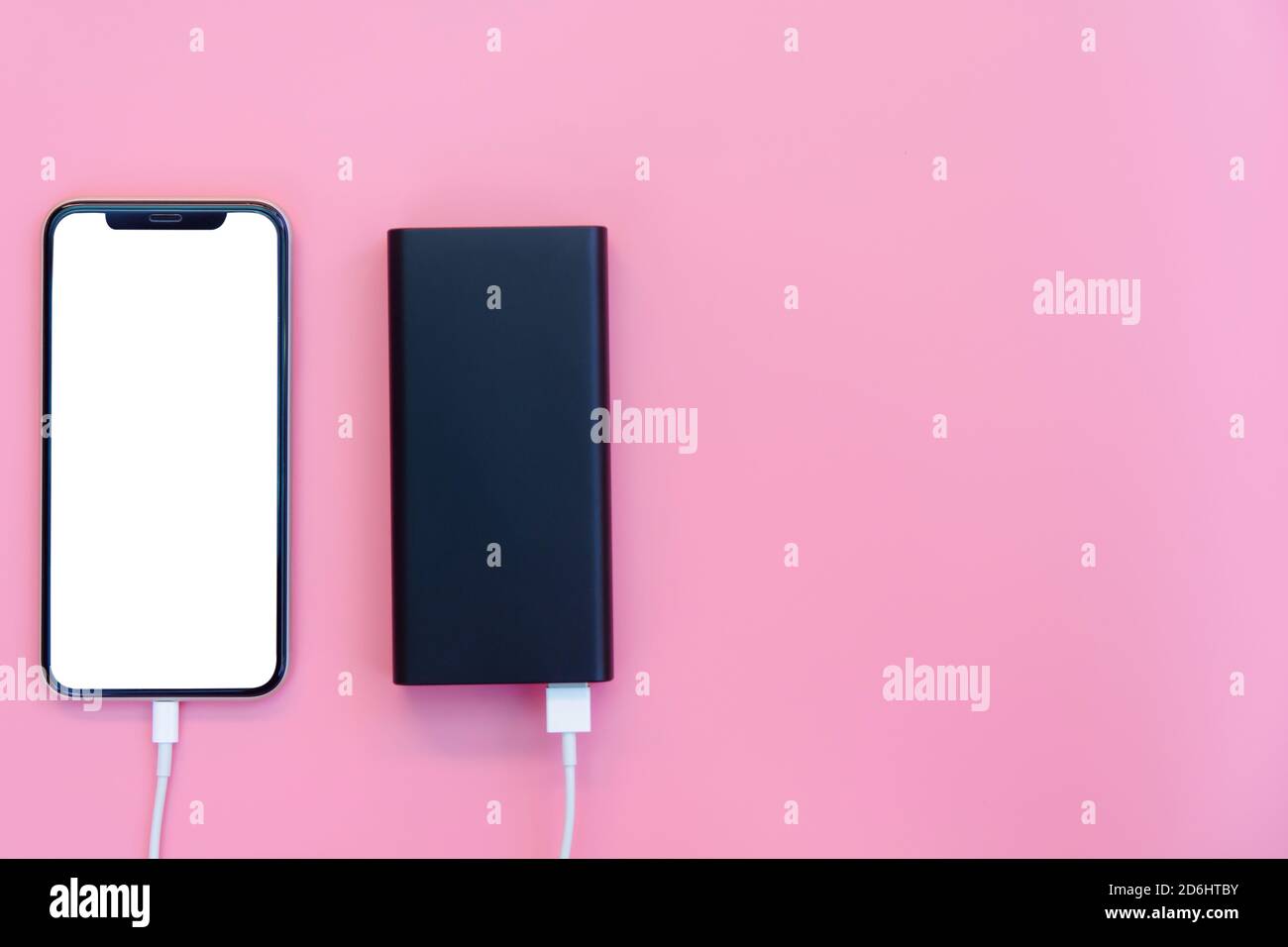Smartphone charging with power bank on pink background. white screen or blank screen with clipping path for copy space. Flat lay Stock Photo