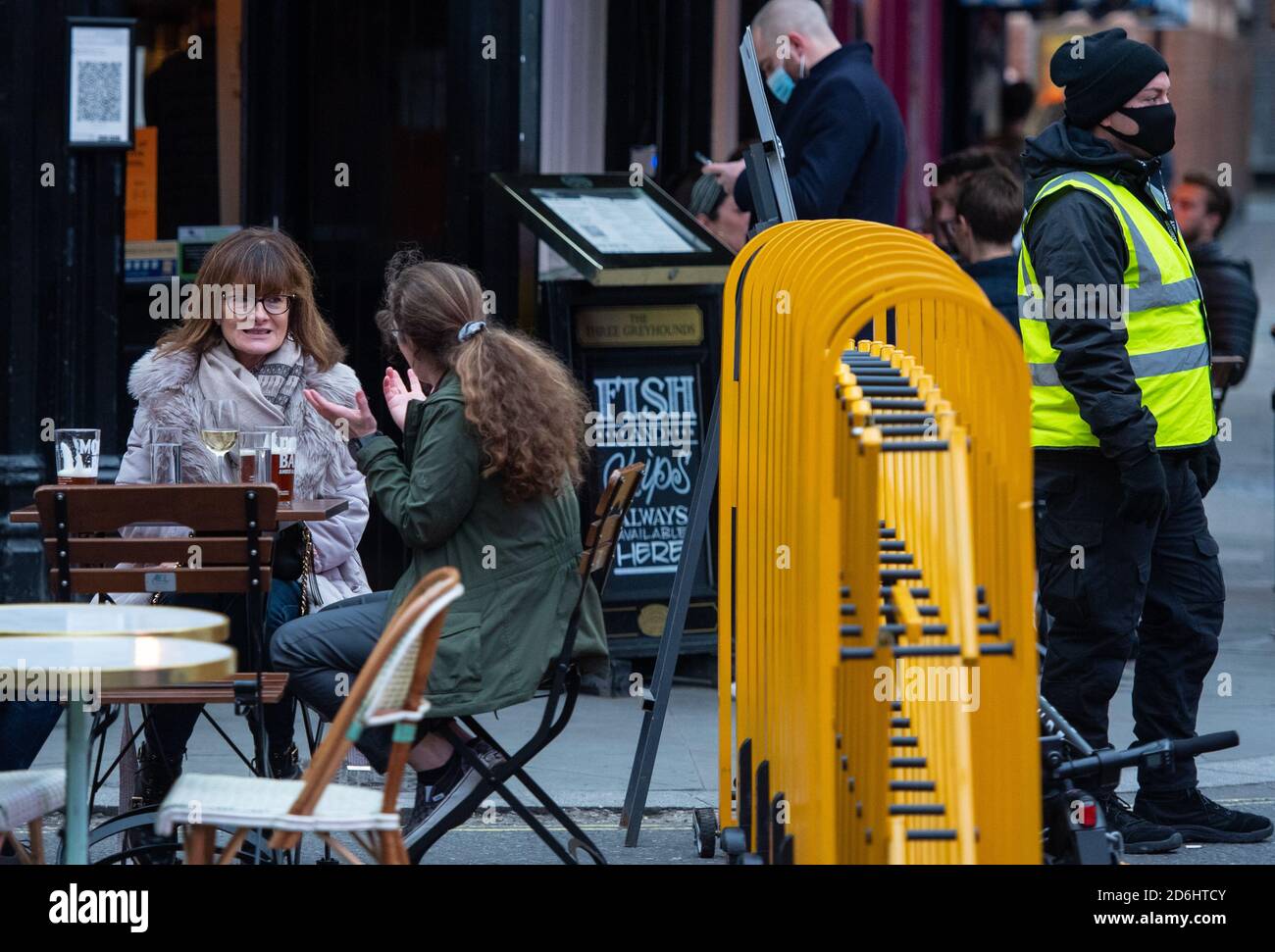 Drinkers outside a pub in Soho, London, on the first day after the city was put into Tier 2 restrictions to curb the spread of coronavirus. Stock Photo