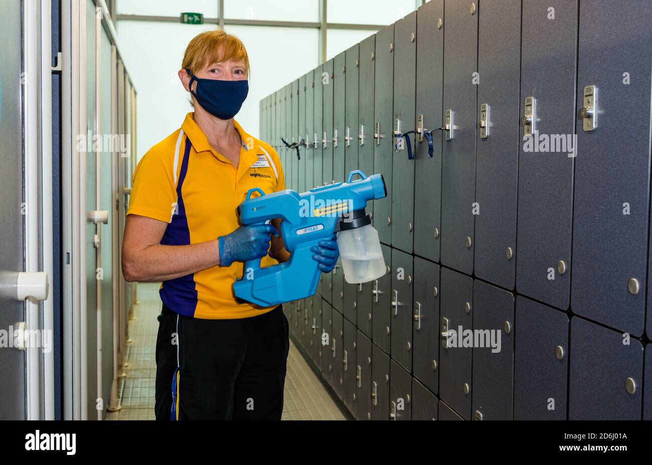 Female staff wearing face mask cleaning lockers with fogger hygiene sprayer in Covid-19 pandemic, North Berwick sports centre, East Lothian, Scotland Stock Photo