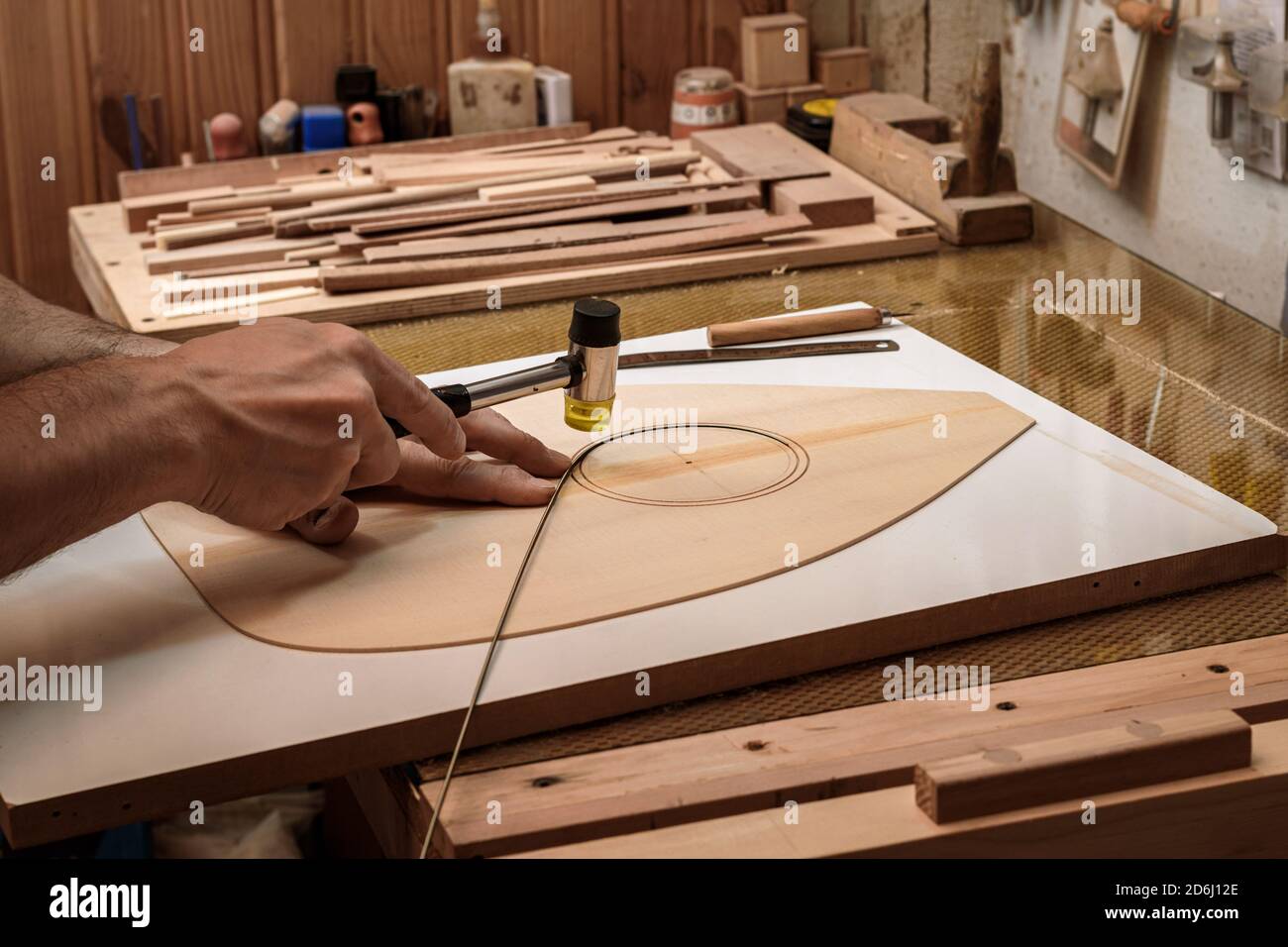 a luthier - instrument maker - inlaying ebony wood strips on the surface of soundboard to give point to whole outlines, guitar rosette. Stock Photo
