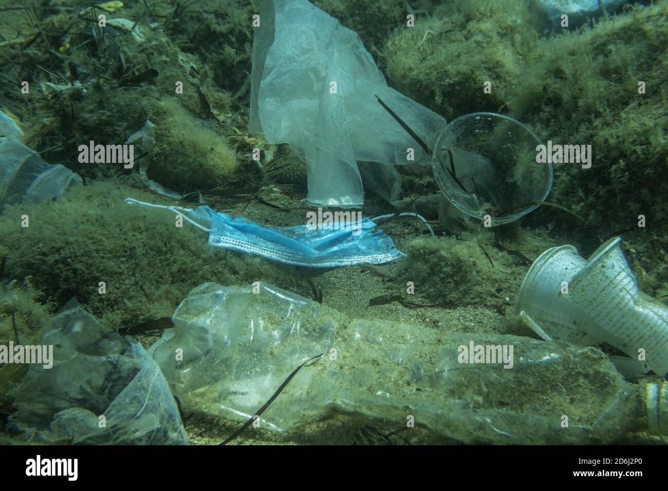 Discarded used medical face mask along with other plastic debris lies on the seabed. Plastic and other garbage polluting in the Adriatic Sea. Becici Stock Photo