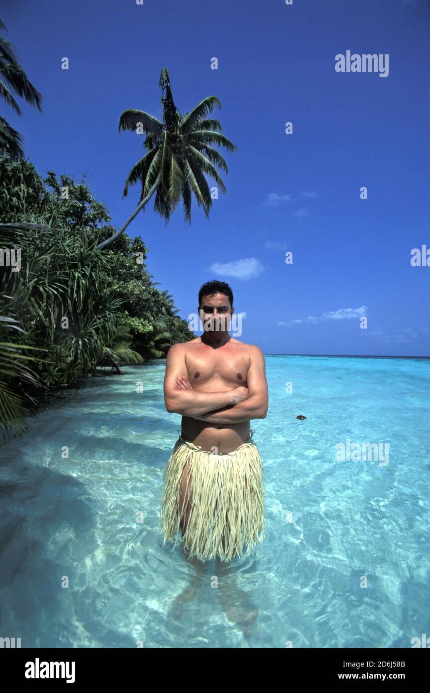 Man with raffia skirt in water, Maldives Stock Photo