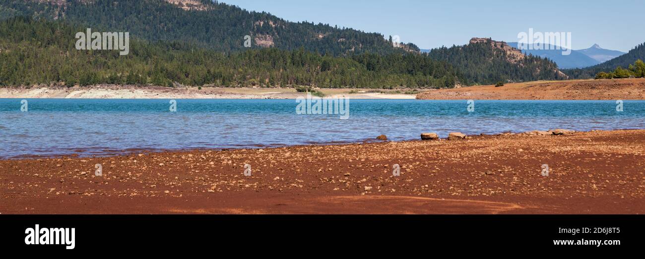 Low water levels reveal red clay and rocks at Lost Creak Lake near Prospect, Oregon located in the Cascade Mountain Range. Stock Photo