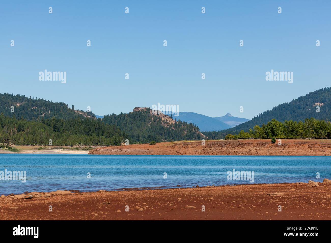 Looking across the surface of Lost Creek Lake to Stewart State Park on the embankment with Needle Eye Rock and Union Peak in the Cascade Mountain Rang Stock Photo