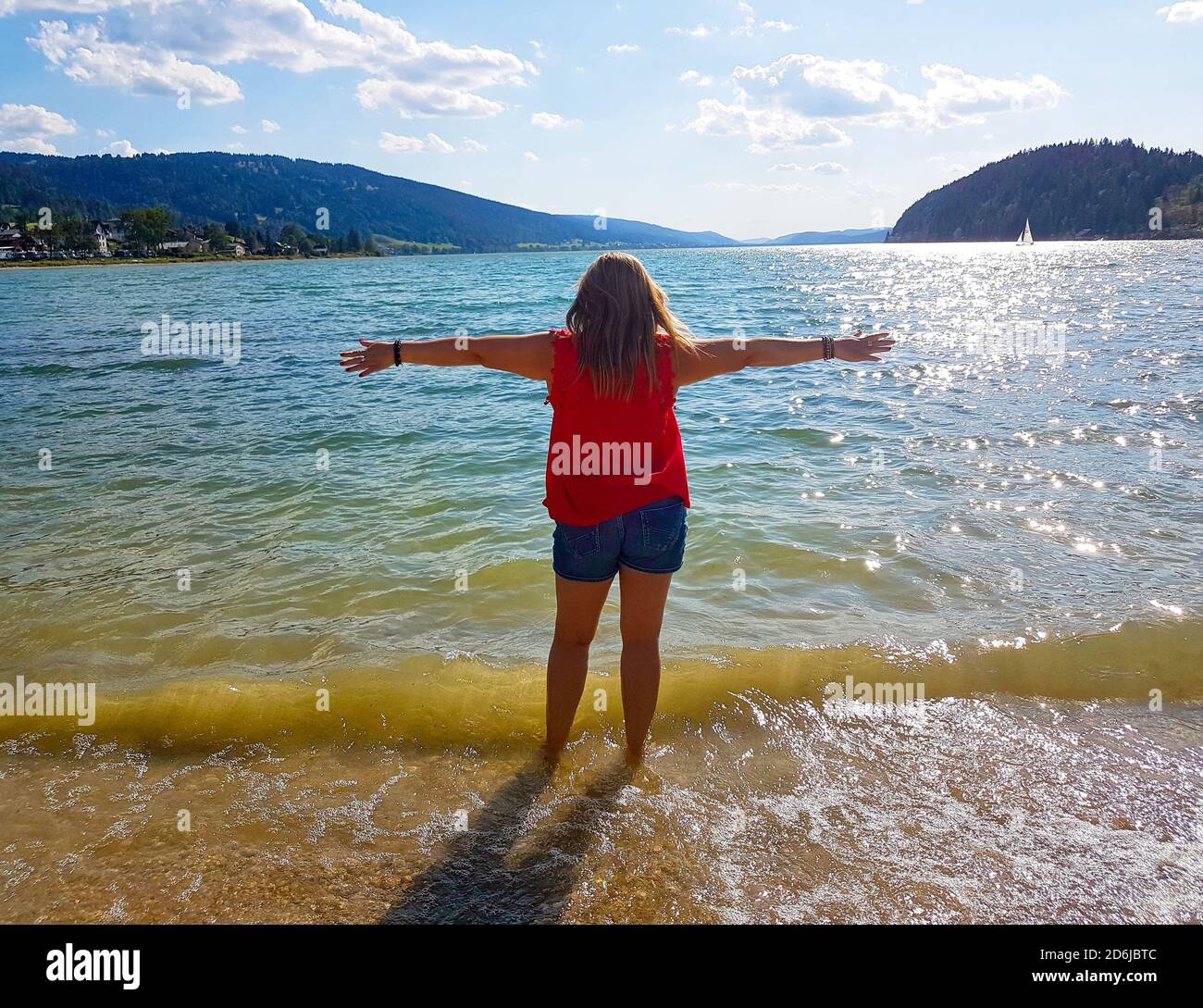 Blonde woman on her back looking at the sea in front of a bay with her ...