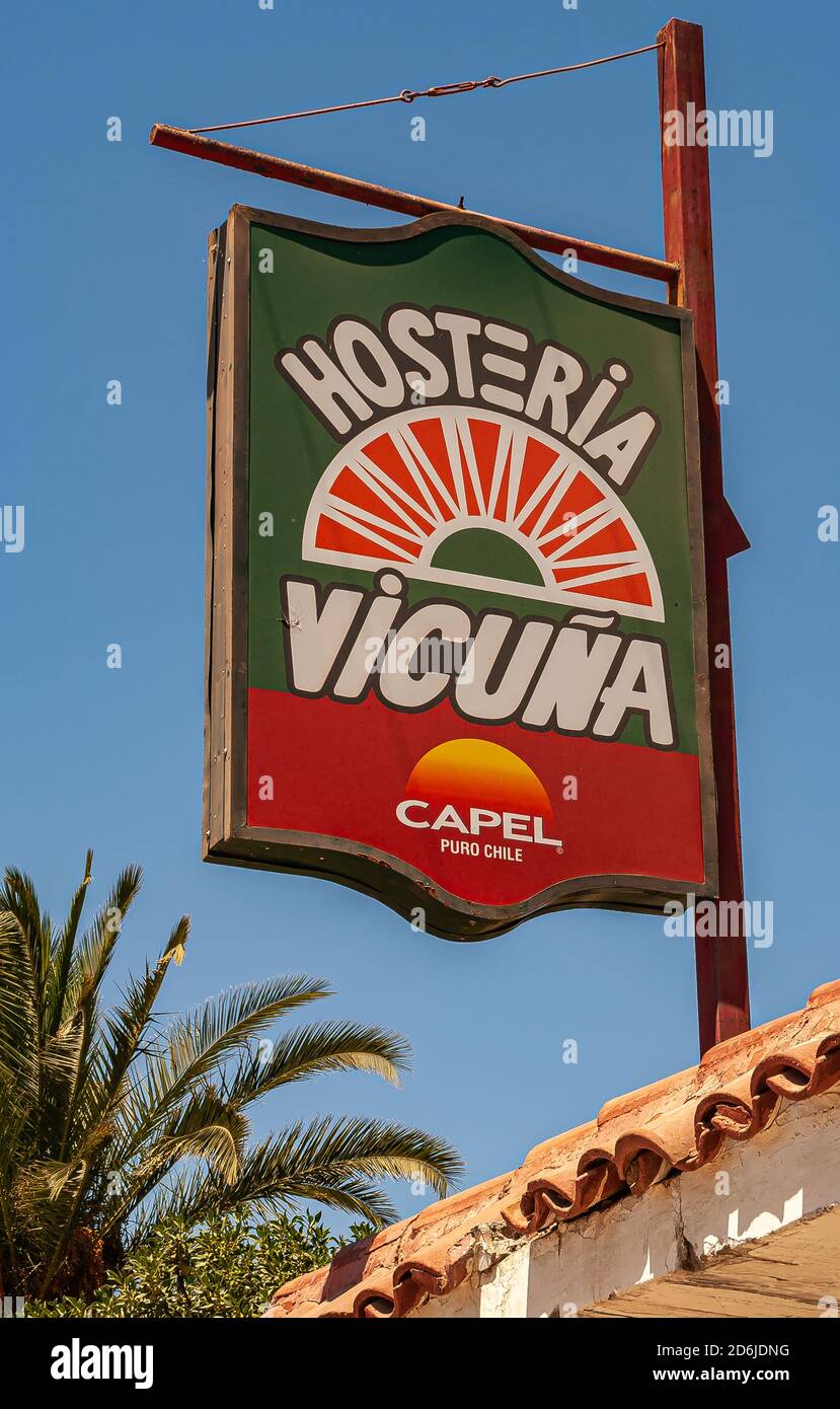 Vicuna, Chile - December 7, 2008: Downtown. Closeup of green-red-white sign hung on pole against blue sky for the local Inn. Some green foliage and pa Stock Photo