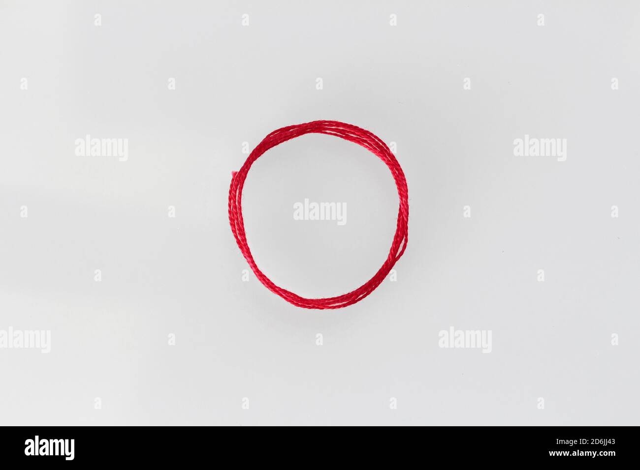 a red silk thread looped in a circle form on a soft white background Stock Photo