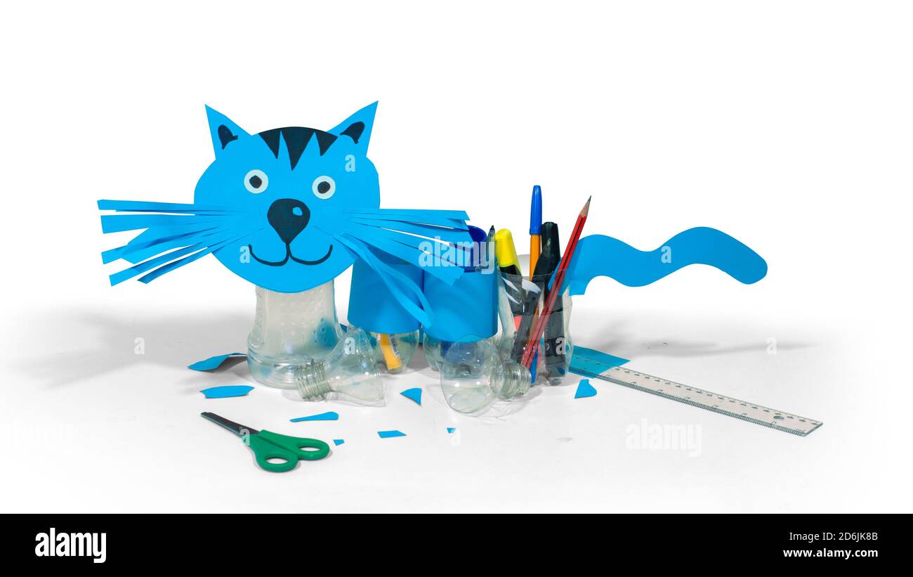 Blue cat made with cardboard and recycled plastic bottles that can be used as pencil holders on table with scissors and ruler on white background Stock Photo