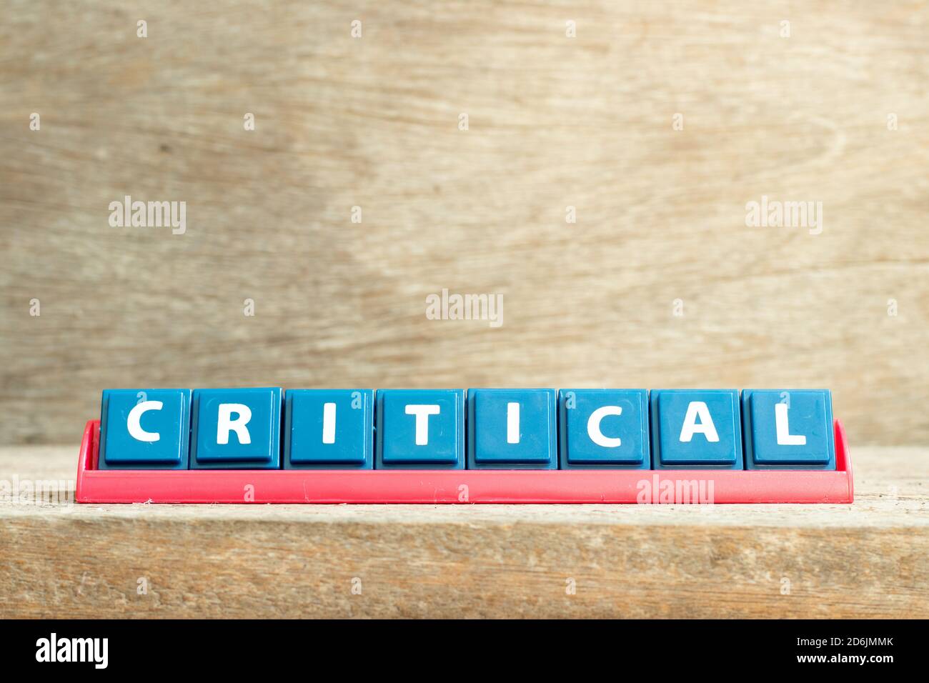 Tile letter on red rack in word critical on wood background Stock Photo