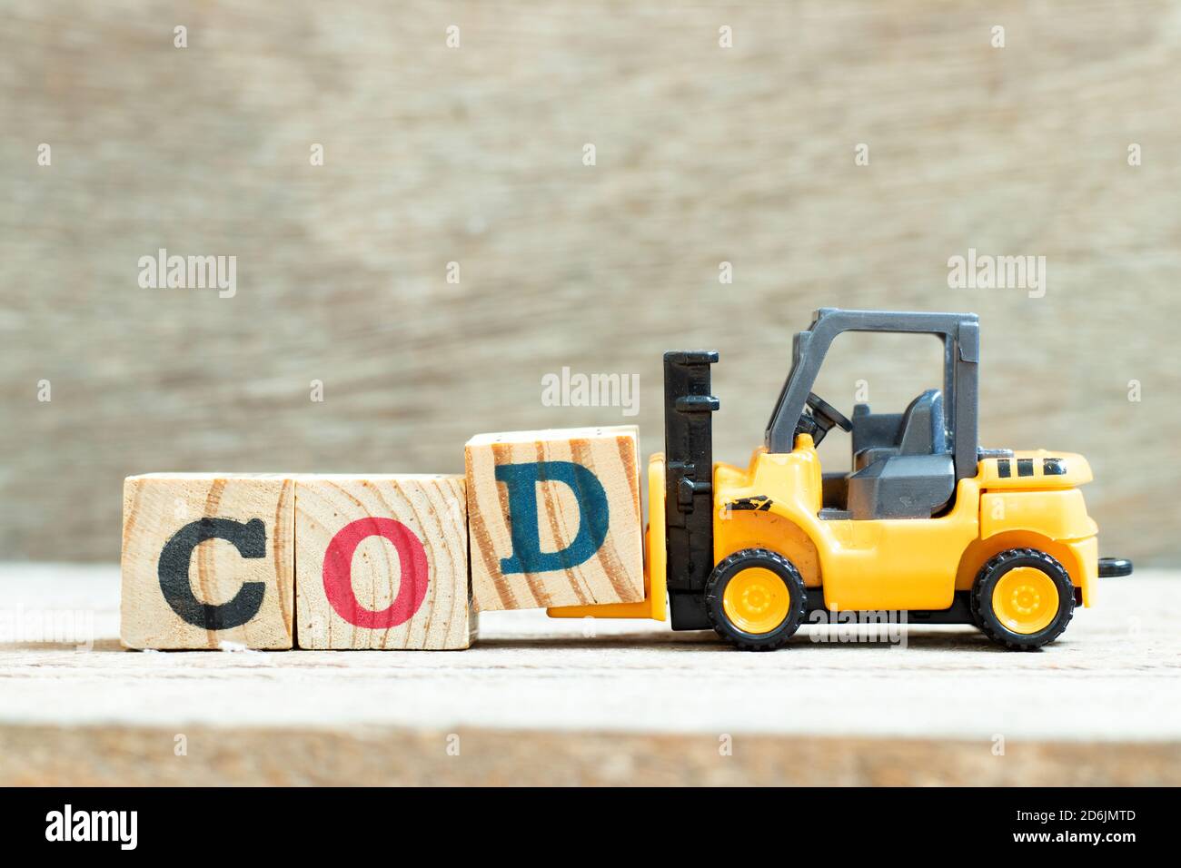 Toy forklift hold letter block D to complete word COD (abbreviation of