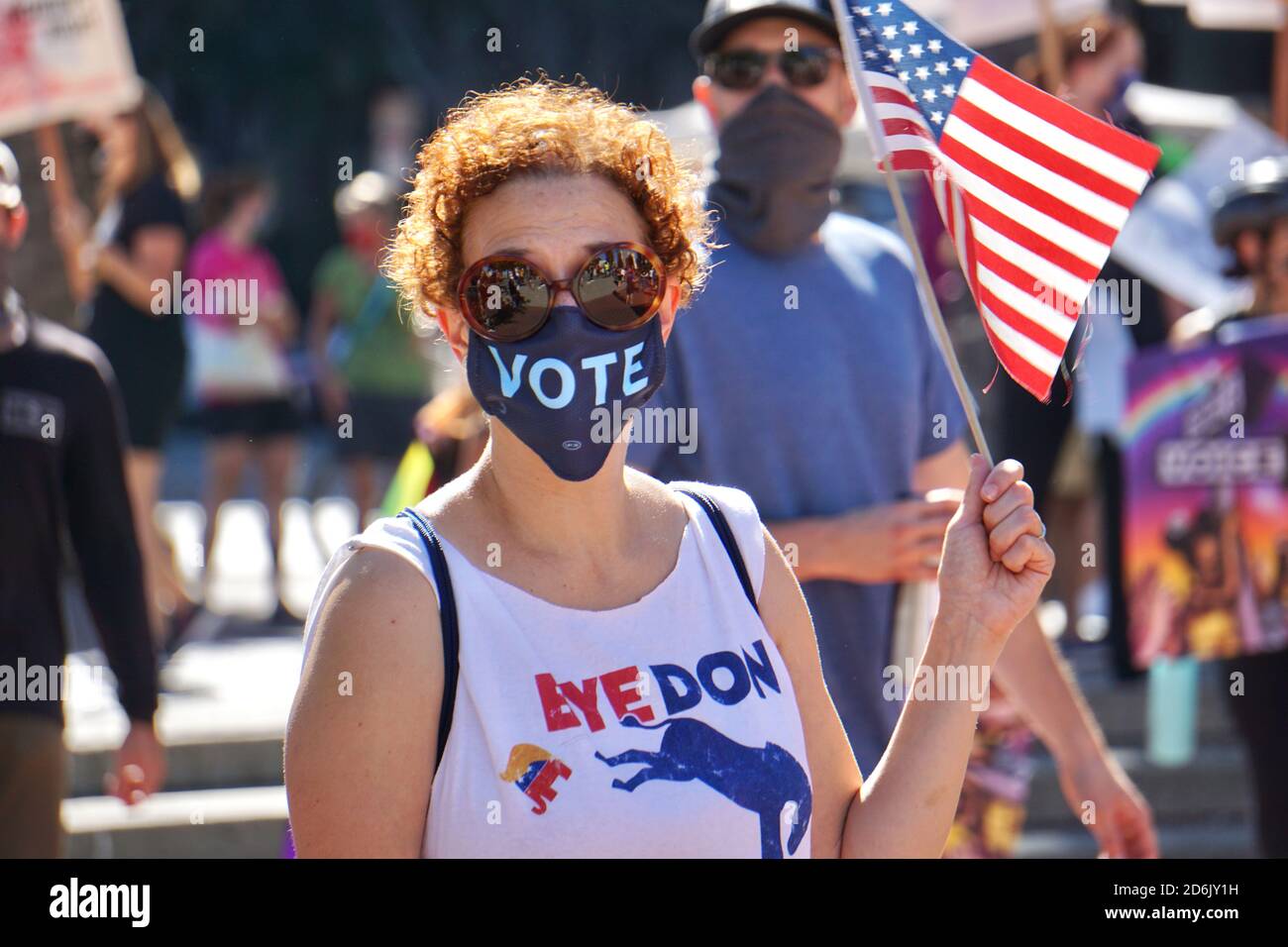 October 17, 2020. San Francisco Women's March. Biden voter wears Vote mask, a Bye Don t-shirt, and holds an American flag shortly before USA Election. Stock Photo