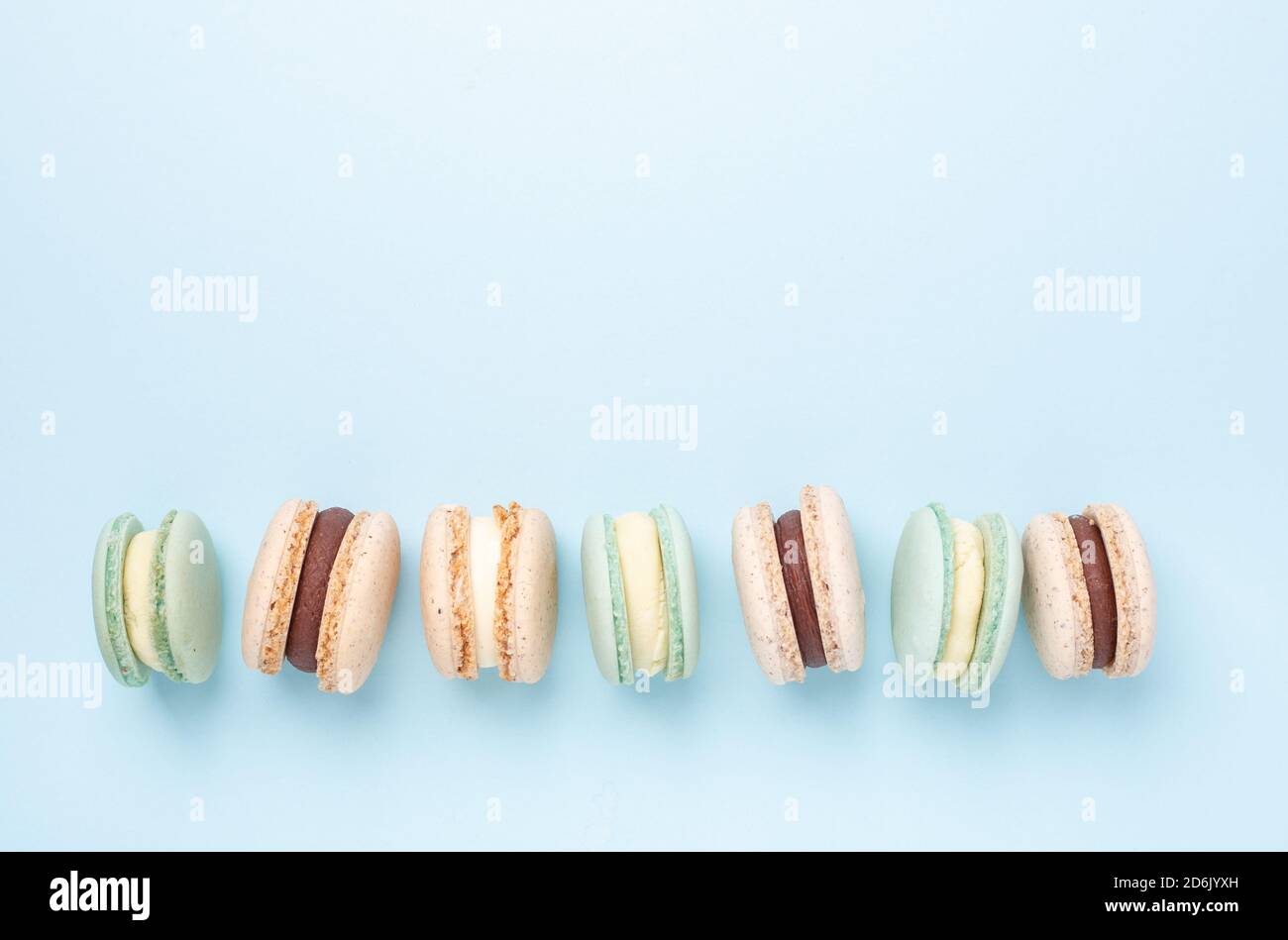 Creative flat lay. Various macarons on blue background. Copy space for your text - Image Stock Photo