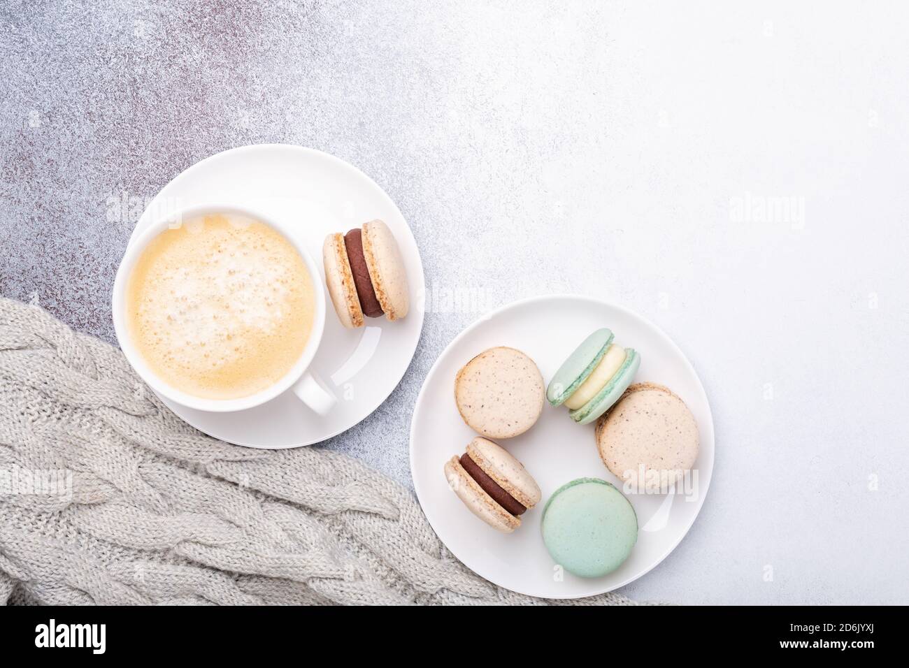 Cup of coffee, sweater and macarons on stone background. Copy space. Flat lay, top view - Image Stock Photo
