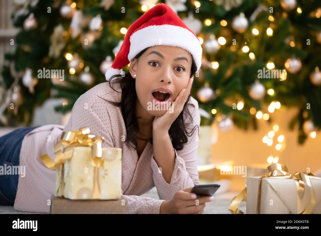 Portrait of shocked biracial woman surprised by Christmas discount Stock Photo