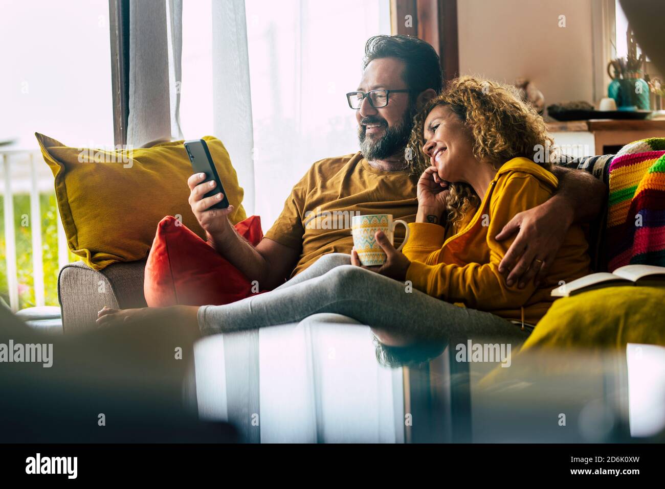 Adult caucasian couple at home enjoy phone call conference with friends - people and technology activity - happy man and woman have breakfast together Stock Photo