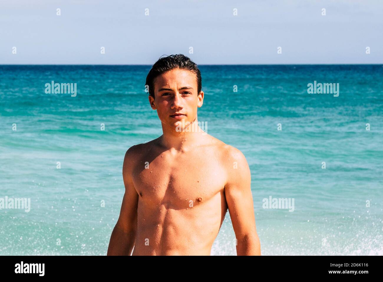 Handsome portrait of young male boy teenager in summer holiday vacation - beautiful youth tourist and blue sea and sky in backgorund - fit body with m Stock Photo