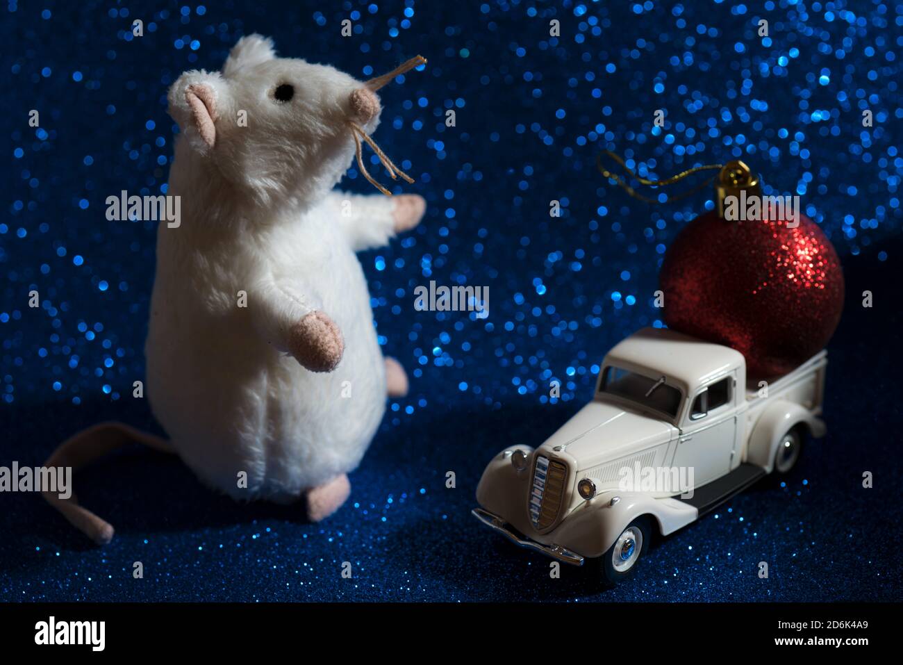 A rat with a retro toy car and red ball on shiny Christmas background Stock Photo