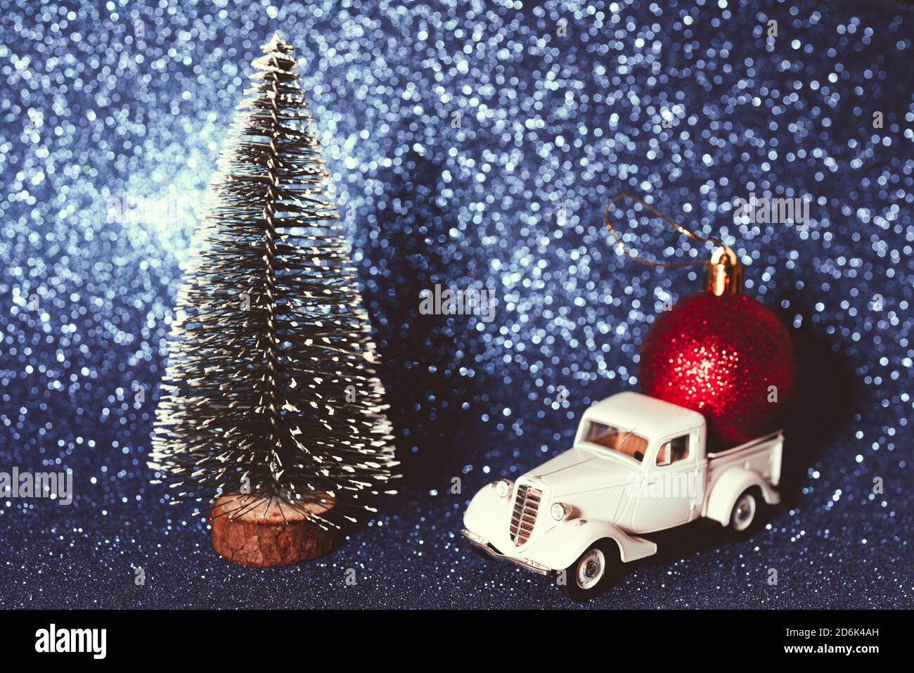 Festive Christmas tree with a retro car and red ball on shiny background Stock Photo