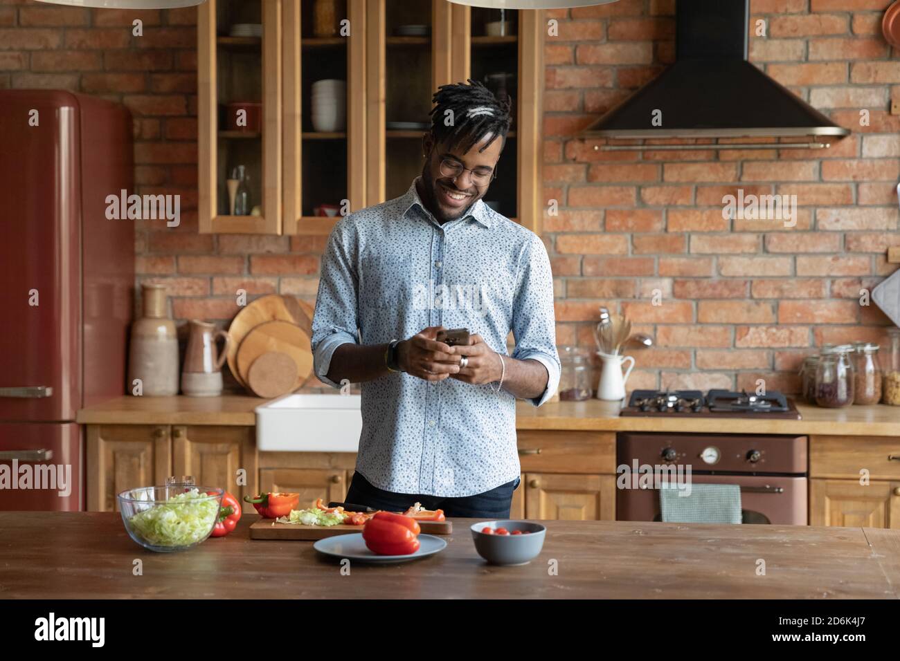 Smiling African American man use smartphone cooking at home Stock Photo ...