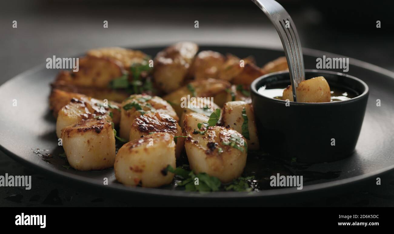 eat roasted scallops with baked potatoes on black plate, wide photo