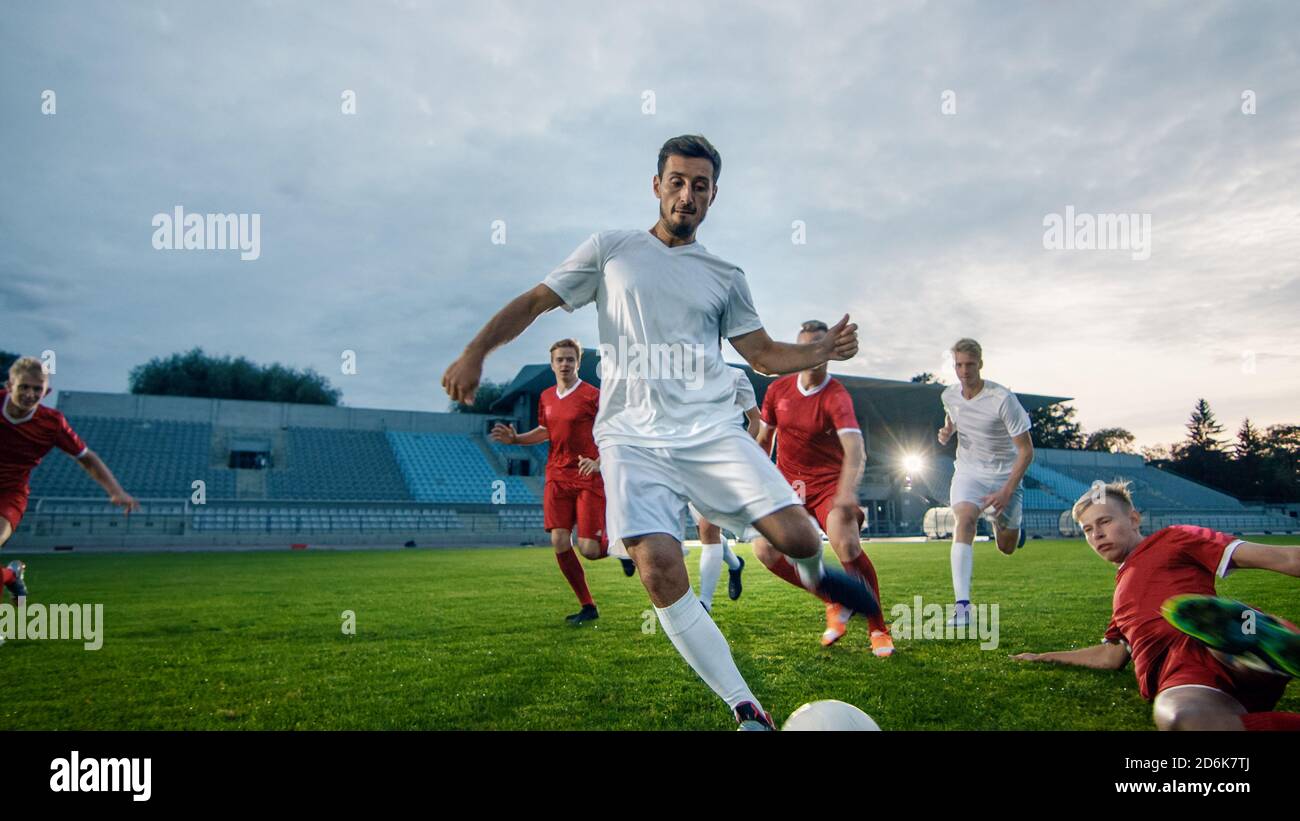 Professional Soccer Player Outruns Members of Opposing Team and Kicks Ball to Score Goal. Soccer Championship on a Stadium. Stock Photo