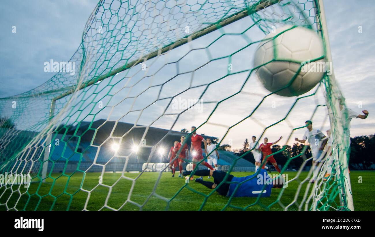 On Soccer Championship Goalkeeper Tries to Defend Goals but Jumps and Fails to Catch the Ball. Shot from Behind the Net with the Ball in it. Whole Stock Photo