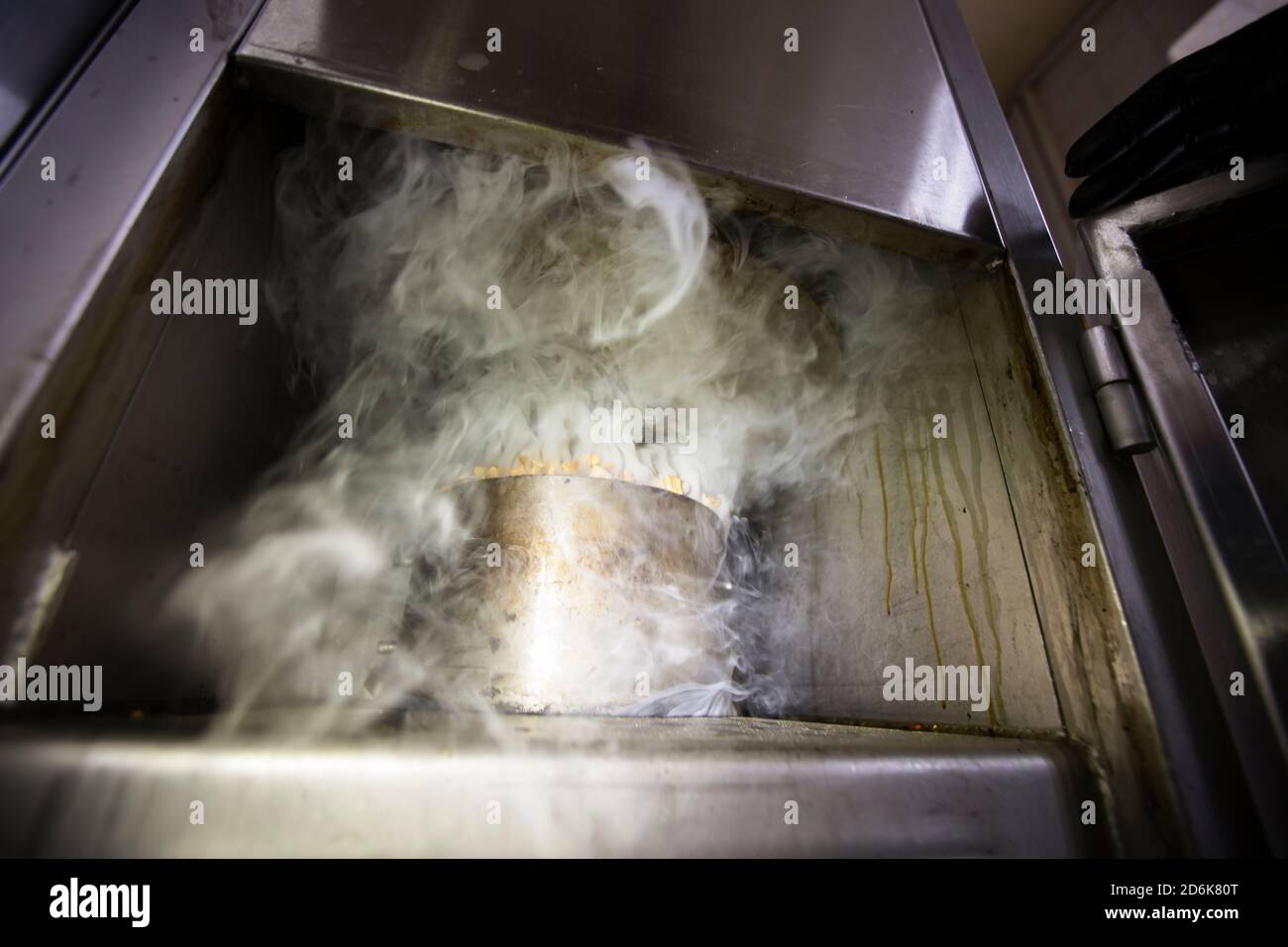 Metal pot with sawdust and smoke in an industrial oven for smoking fish