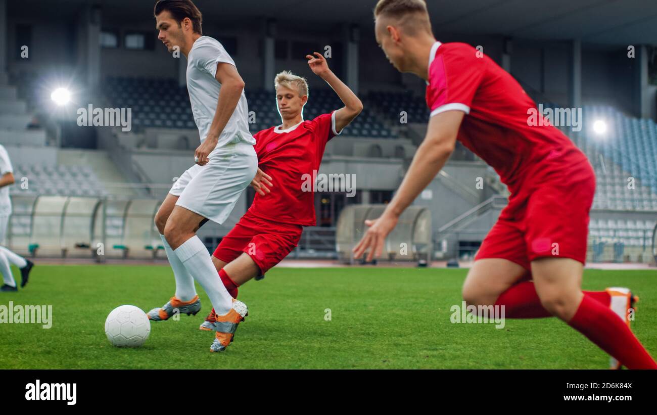 Professional Soccer Player Leads with a Ball, Masterfully Dribbling and Bypassing Sliding Tackles of His Opponents. Two Professional Football Teams Stock Photo