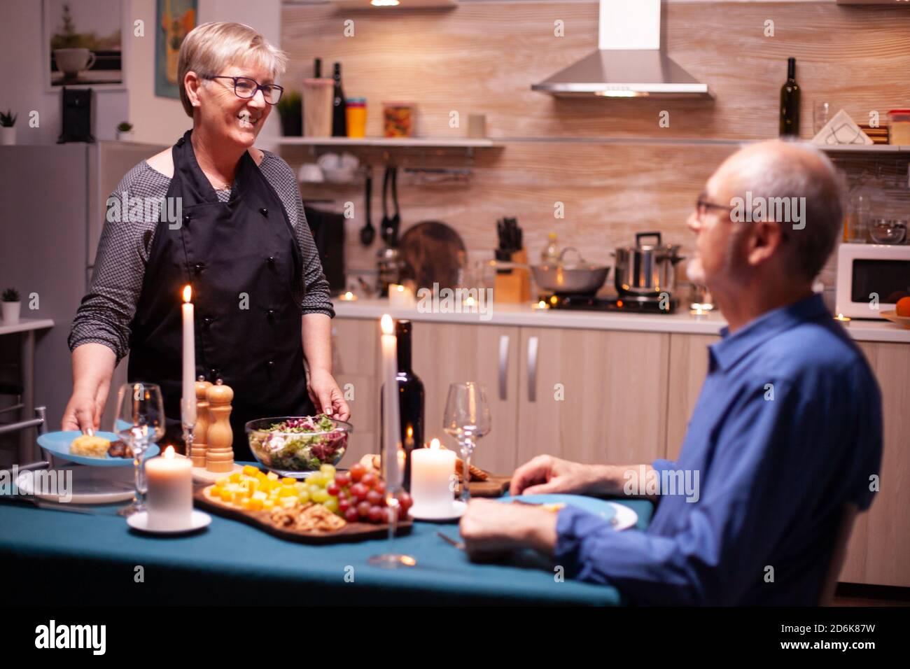 Husband sitting at dinner table and wife serving tasty food for