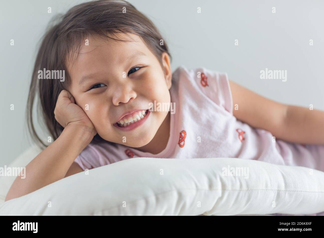 Portait cute happy asian little girl lying in bed with a big smile. Stock Photo