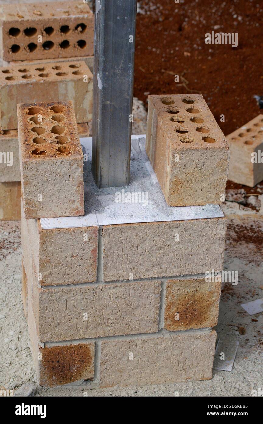 New house build using a steel frame. Bricks being laid around a steel post. White layer is a termite barrier. Queensland, Australia 2006) Stock Photo